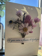 Greeting card with floral design and text on a surface with a blurred background