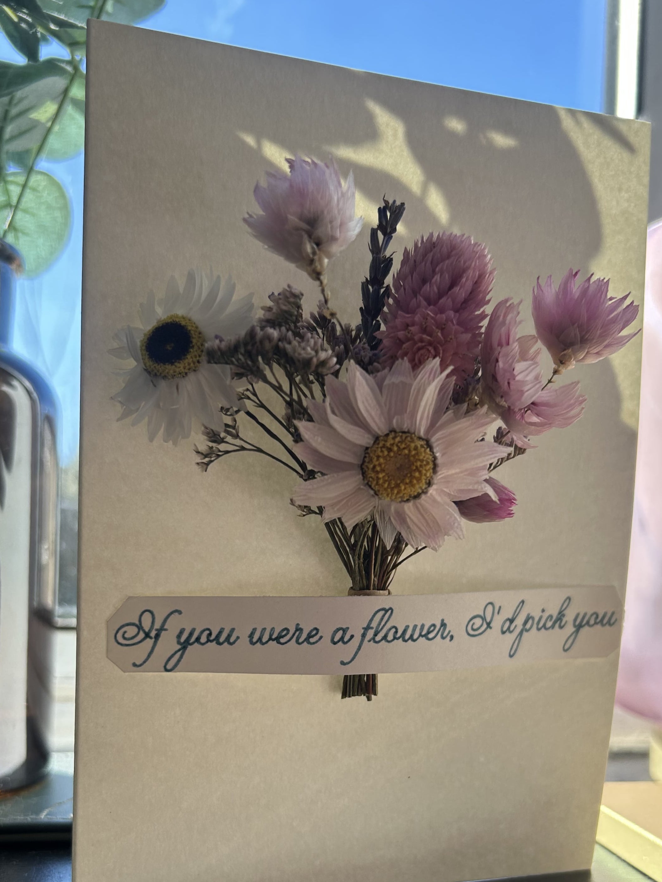 Greeting card with floral design and text on a surface with a blurred background